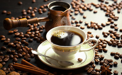 Black coffee in a cup on the background of coffee beans in a composition with accessories