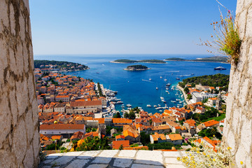 View through the walls of the old harbor in Hvar, Croatia - obrazy, fototapety, plakaty