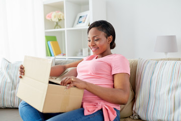 happy pregnant woman opening parcel box at home