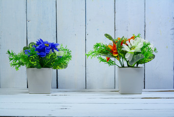 home decoration, 2 white vase with blue and orange flowers on wood table and wood wall