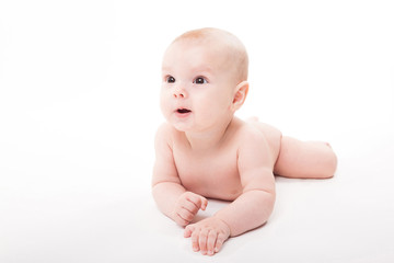 Naked smiling baby lying on his stomach on a white background and looking at the camera
