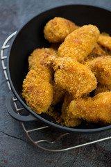 Close-up of breaded chicken wings served in a cast-iron pan, vertical shot