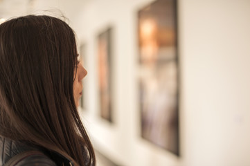 Young woman looking at modern painting in art gallery