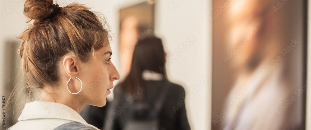 Wall mural young woman looking at modern painting in art gallery