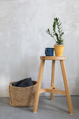 Simple interior with basket and table with arranged flowerpot and cup on top.