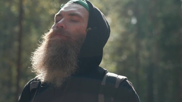 The Forester in the forest enjoying the sunshine and warmth. The bearded man at peace and happy in nature.