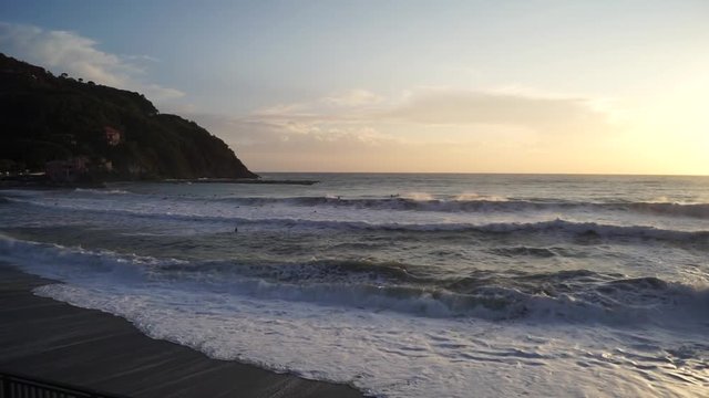 Paesaggio di mare in tempesta al tramonto con surfisti
