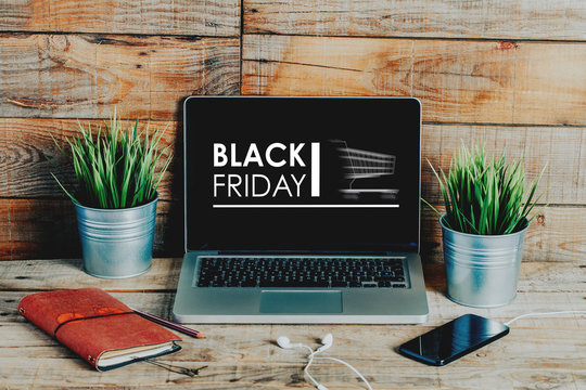 Black friday advertisement in a laptop computer screen placed on a wooden workplace.