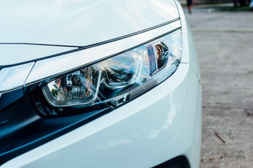 Front view detail of a car headlight,White car.