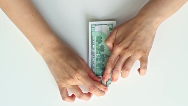 Top view with fast motion of female hands folding swan origami from dollar bill
