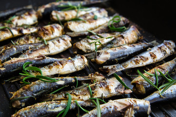 Sardines in a frying pan grilled with spices and rosemary.