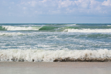 Sea coast waves rolling on empty beach, stormy cloudy sunrise