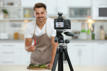 Young blogger recording video on camera in kitchen