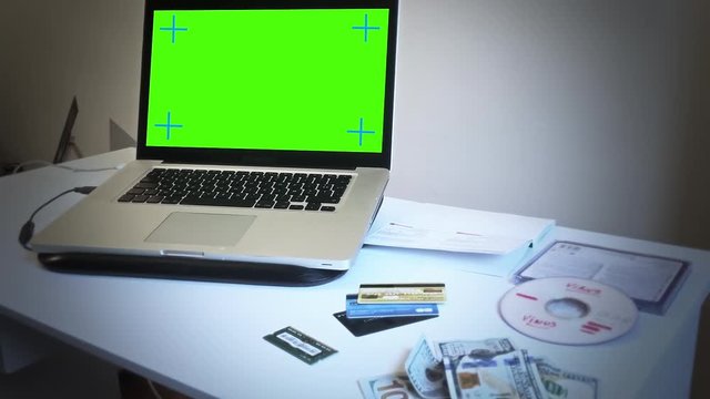 Green Screen Laptop In A Hacker Crime Scene, Pan Movement. Green screen laptop next to stolen credit cards, dollar bills and virus dvd simulating a hacker crime scene