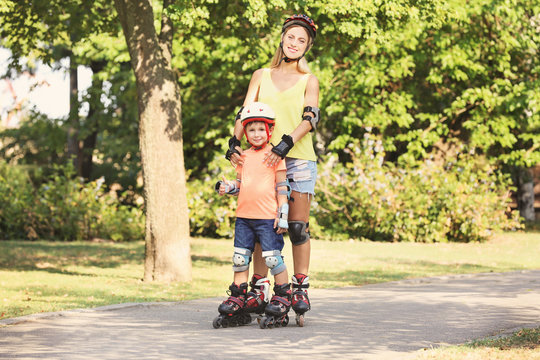 Mother with son on roller skates in summer park