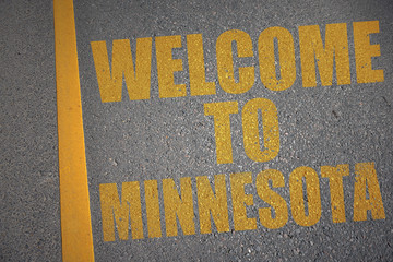 asphalt road with text welcome to minnesota near yellow line.