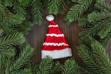 Christmas fir tree branches and Santa Claus red hat  on dark rustic wooden background