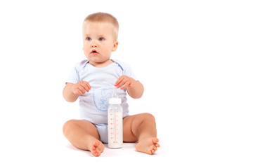 cute confused baby boy in blue pijamas with milk