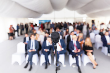 Business conference. Corporate presentation. Microphone in focus against blurred audience.