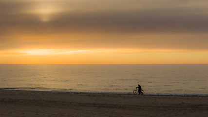 Nastrojowe zdjęcie rowerzysty na tle zachodu słońca na plaży nad morzem.