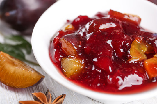 Bowl with delicious plum jam on table