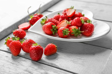 Heart shaped plate with strawberries on wooden background