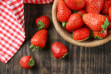 Bowl with fresh strawberries on wooden table