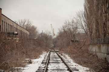 Narrow-gauge railway in industrial area. Snowfall with the fog. 