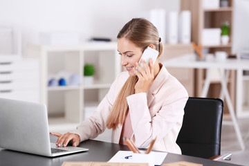 Young woman talking on phone in office