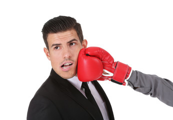 Hand of woman in boxing glove hitting businessman on white background