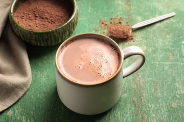 Cup with yummy cocoa drink on color table