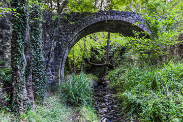 Mountain stream and arch of stone bridge