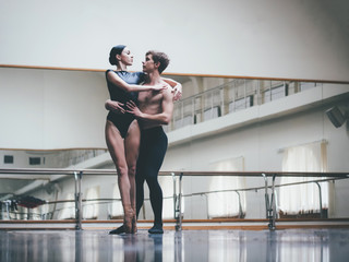 Young man practicing in classical ballet with young beautiful woman in black clothing in the gym or...