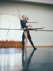 Young man practicing in classical ballet with young beautiful woman in black clothing in the gym or ballet hall. Couple jumping dancing sensual dance. Minimalism interior, © kohanova1991