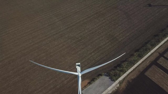 Aerial shot of rotating wind turbines on farmland near ocean