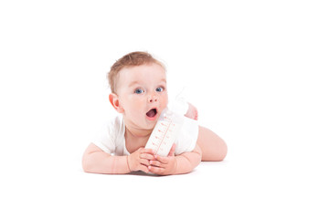 cute pretty baby boy in white shirt lies on tummy with milk bottle