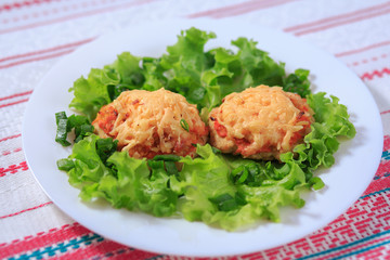 Meat cutlet with carrots and cheese on a white plate with greens
