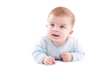 cute pretty little boy in blue shirt lies on belly