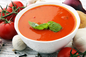 Tomato soup in a white bowl,tomatoes and parsley on a wooden background.