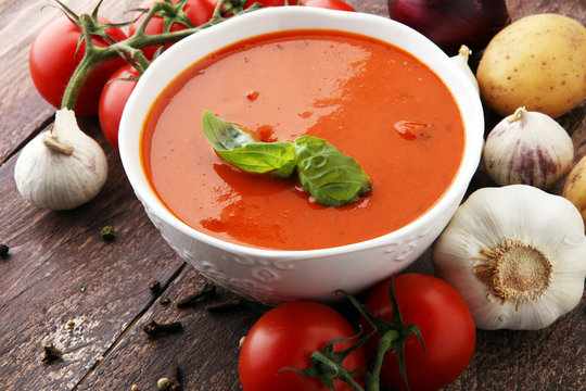 Tomato soup in a white bowl,tomatoes and parsley on a wooden background