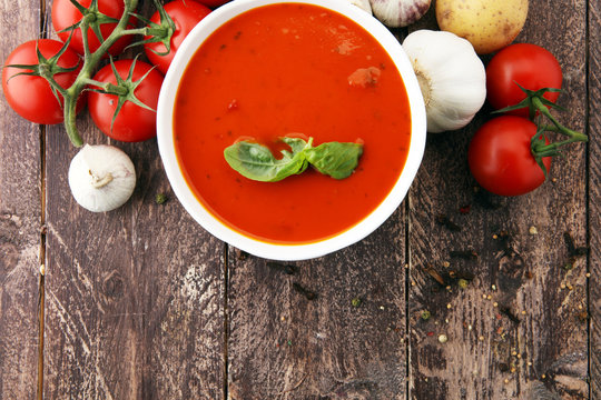 Tomato soup in a white bowl,tomatoes and parsley on a wooden background