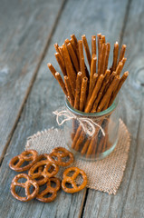 Salted sticks in a glass and on wooden table, with a selective focus.