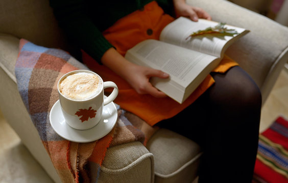 Cup of cappuccino and girl reading a book