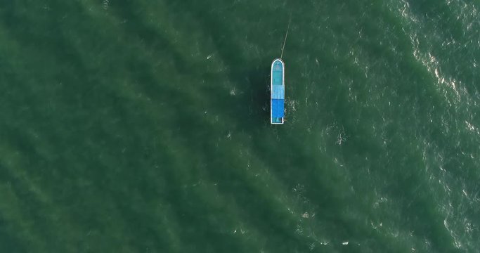 Aerial view blue boat sails on shallow turquoise ocean