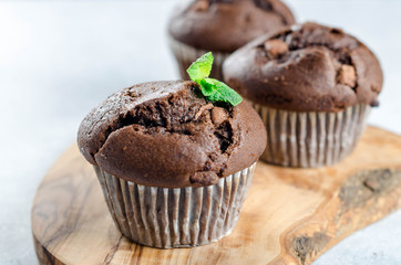 Three chocolate muffins on a wooden board, closeup