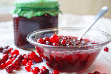 Jam in a bowl, berries and a jar of jam on a white tablecloth