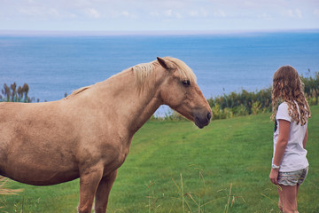 Mädchen schließt Freundschaft mit Pferd vor Meer Hintergrund