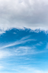Naklejka na ściany i meble Cloudy sky background. Simple cloudscape with white clouds on bright blue sky. Vertical view