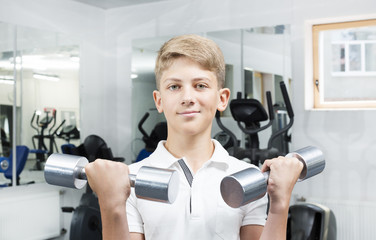 Fototapeta premium The teenager is engaged in power fitness in the gym.