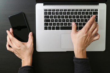 cyber security internet and networking concept.Businessman hand working mobile phone on laptop computer background